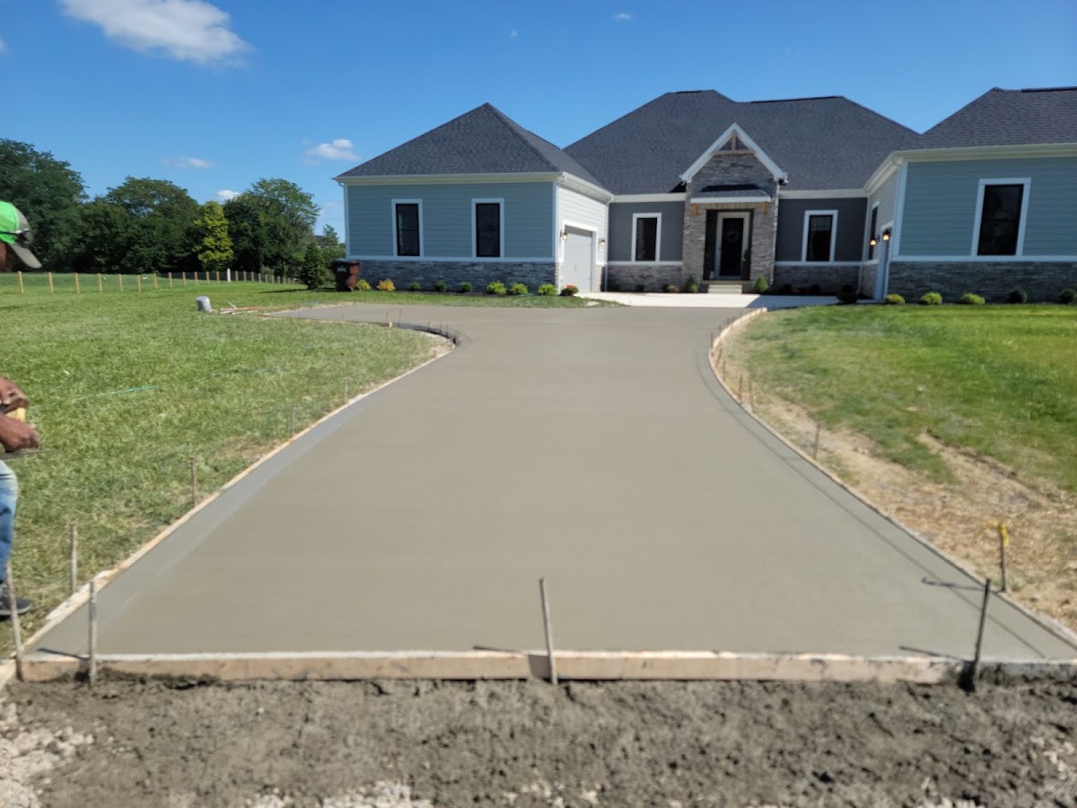 Freshly poured curved concrete driveway at a new-construction home