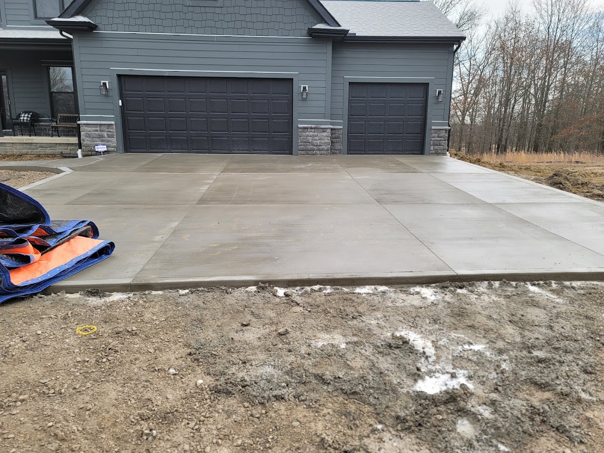 Large finished concrete driveway in front of a three-car garage